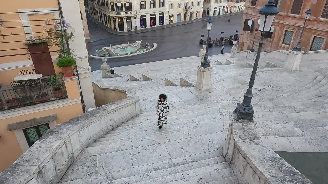 在黎明的意大利罗马，时尚女人走在空旷的西班牙台阶上，无人机拍摄的电影镜头视频下载