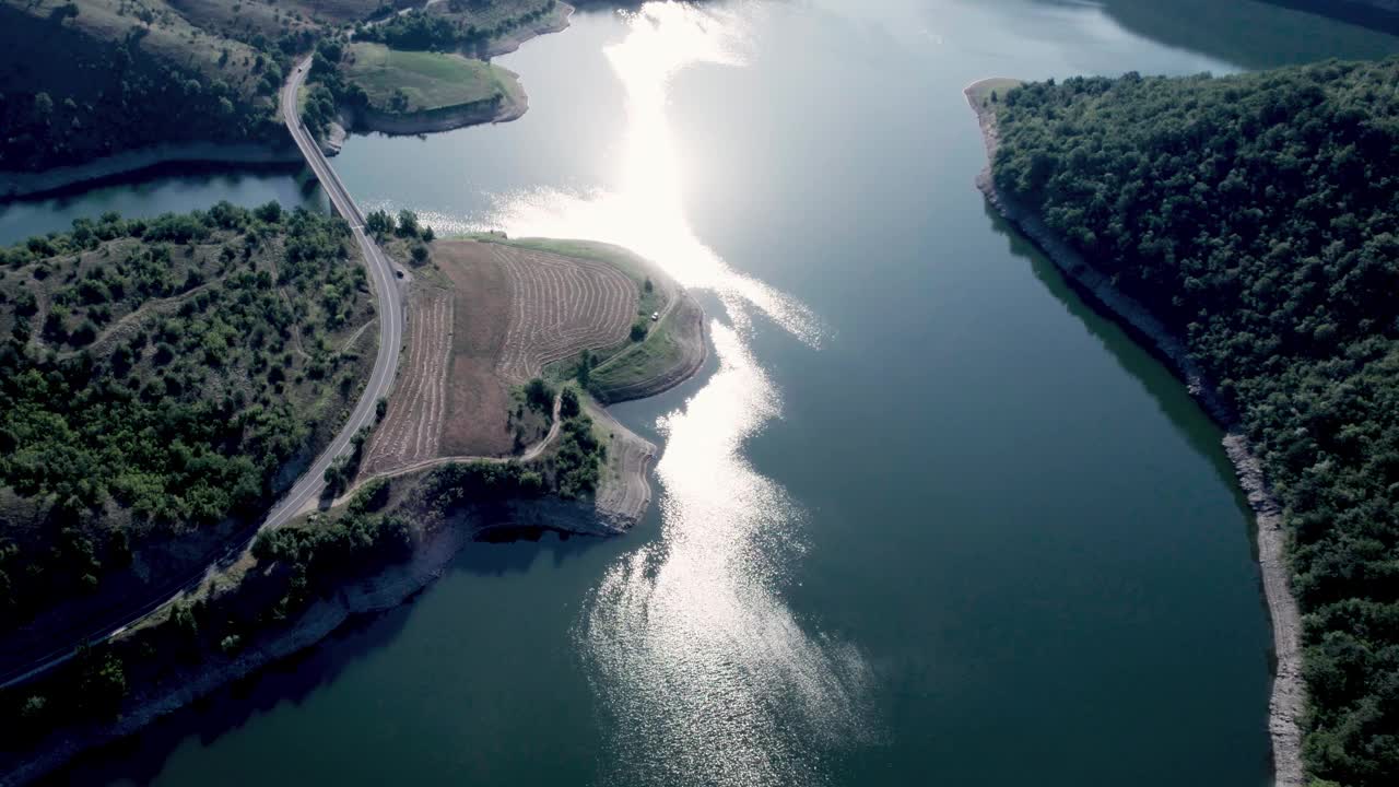 航拍画面显示，一辆汽车在风景如画的湖景上驶过一座桥视频下载
