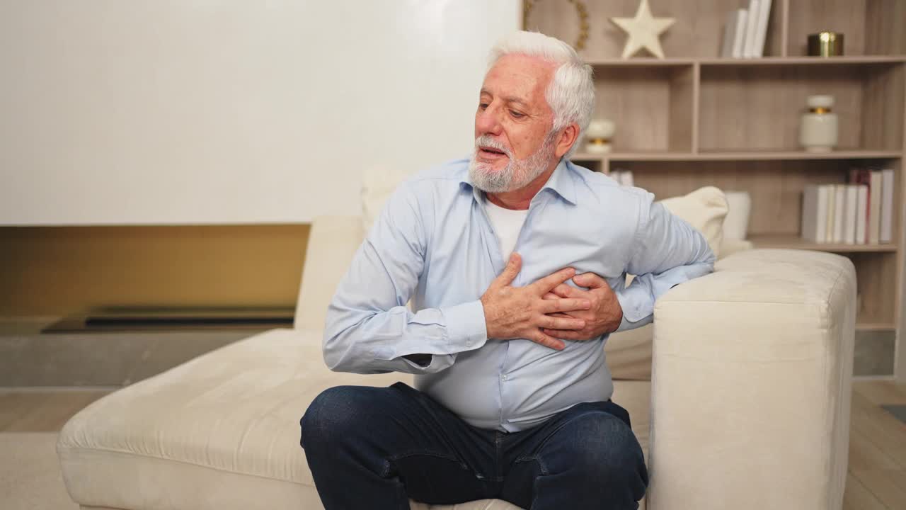 心脏疼痛，心脏病发作。不幸的中年老人患有胸痛心脏病发作和健康问题在家里。成熟的老爷爷摸胸经历梗塞。视频下载