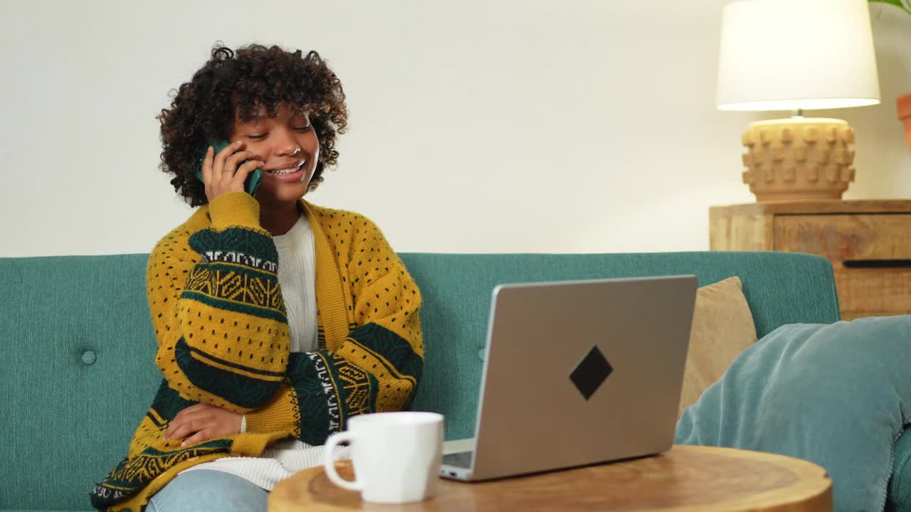 非裔美国女性自由职业者在家庭办公室用笔记本电脑打电话。快乐的商务女孩正在进行虚拟会议。在室内工作的妇女使用手机笔记本电脑进行通信。远程工作。视频下载