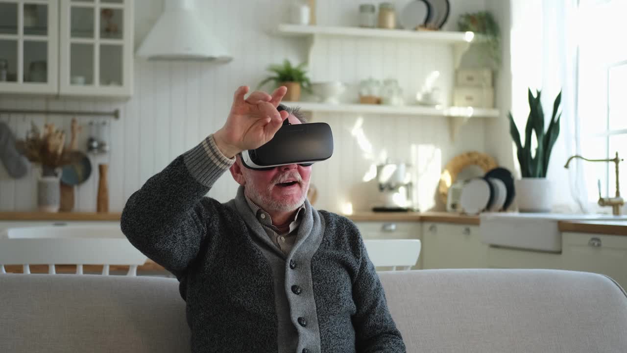 兴奋的成熟老年男子在家中戴着使用虚拟现实的虚拟现实头盔。爷爷在虚拟现实头盔上体验VR时触摸空气。模拟高科技视频游戏。视频下载