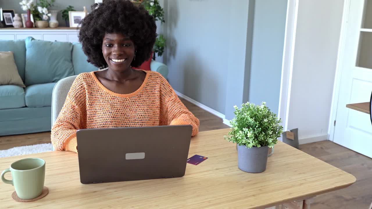 一个微笑的女人在轻松的环境中用笔记本电脑购物视频下载