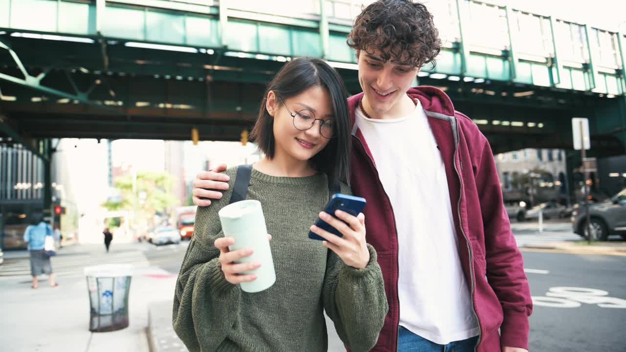 年轻的千禧一代夫妇在城市里，用着智能手机和喝着咖啡走视频素材