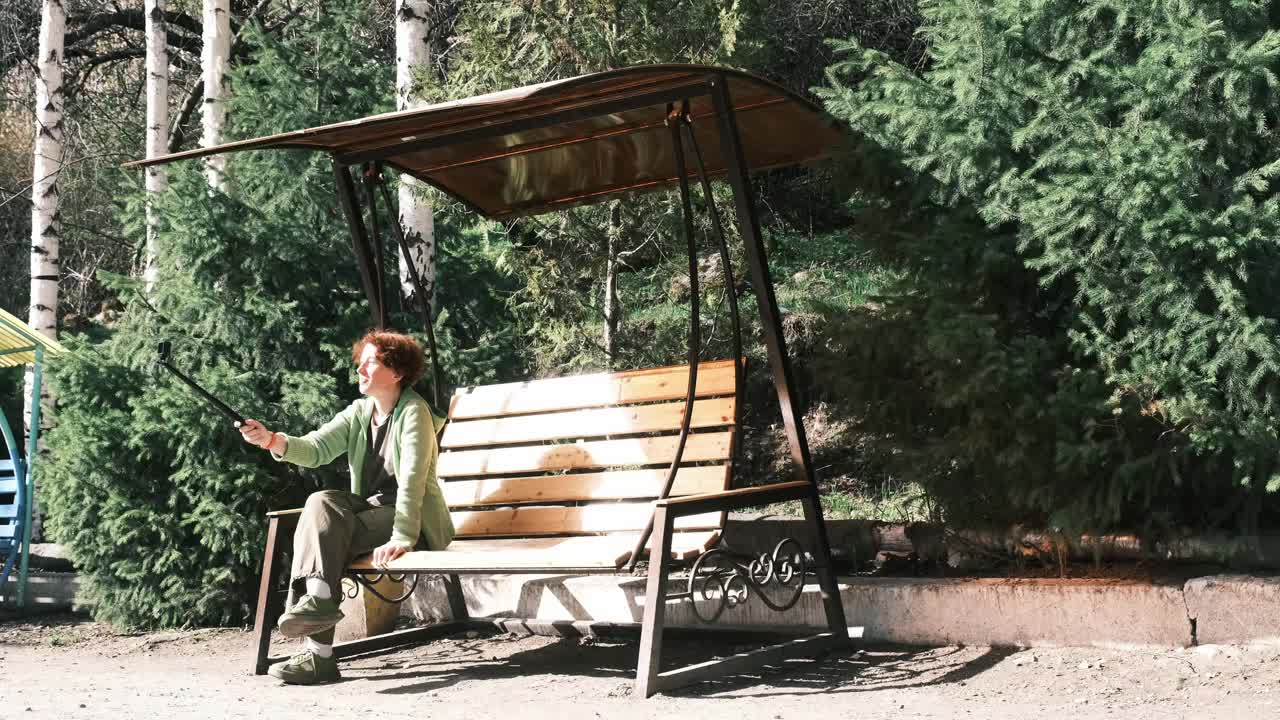 一位女游客正坐在公园的长椅上看电视视频下载