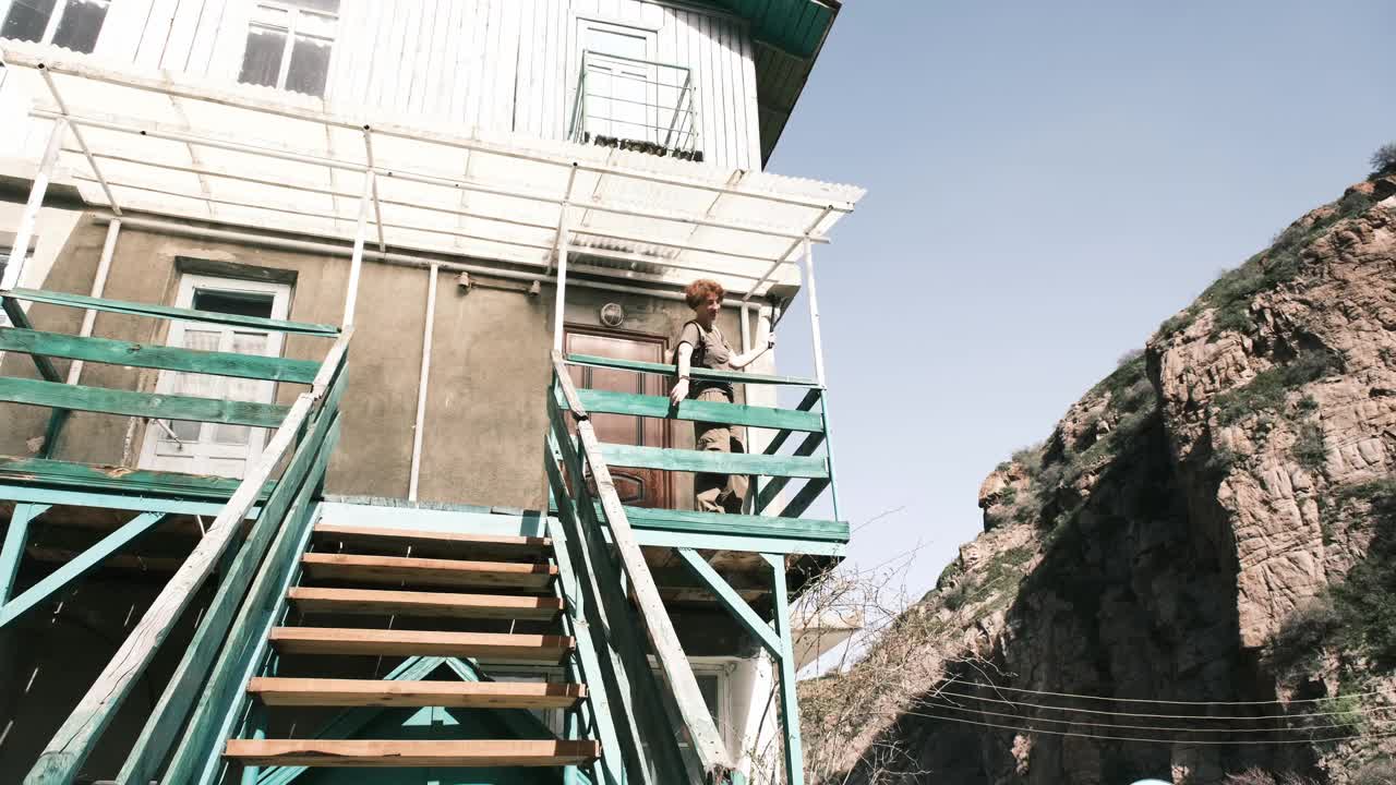 一个成熟的女人正在用动作相机拍摄山河上废弃的旧旅馆视频下载