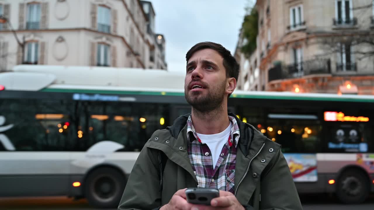 年轻的商人在巴黎户外使用电话。男子正在用智能手机发短信视频下载