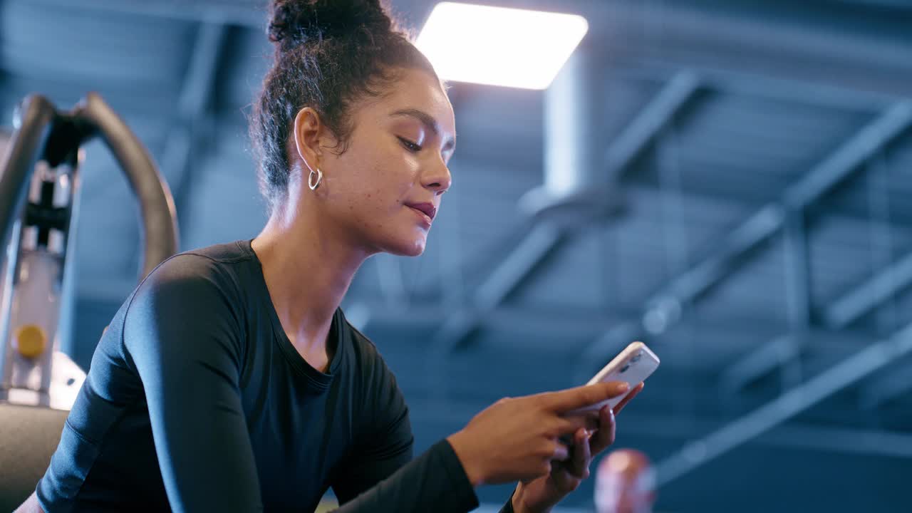 女人，电话和微笑在健身房健身与短信，手机聊天和打字放松。私人教练，运动员和检查通知，锻炼应用程序和在线锻炼休息视频下载