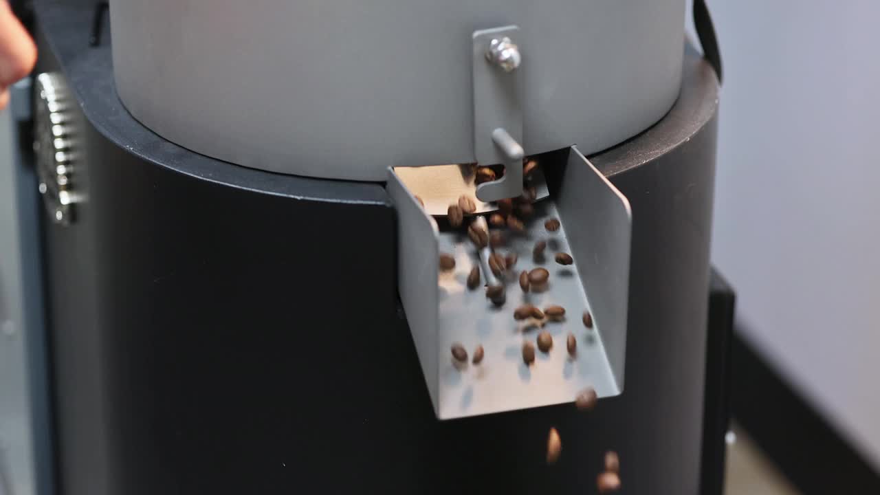 烘焙后的咖啡豆从排气挡板冷却器中溢出，一个烘焙工厂的过程正在进行中。视频下载