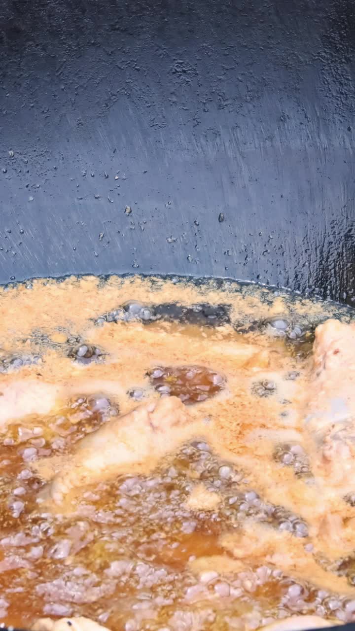 裹着面包屑的鸡腿在黑锅里用热油油炸视频下载