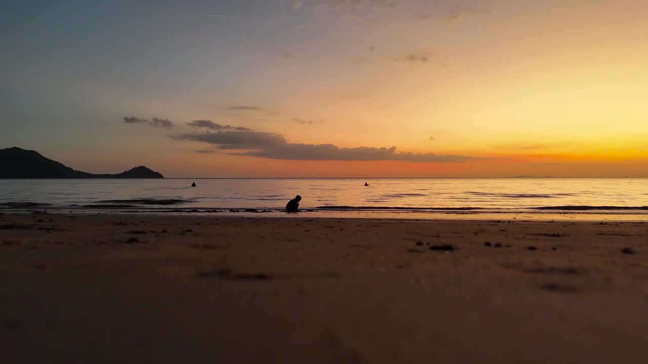 夕阳下，一个男孩在沙滩上玩耍视频下载