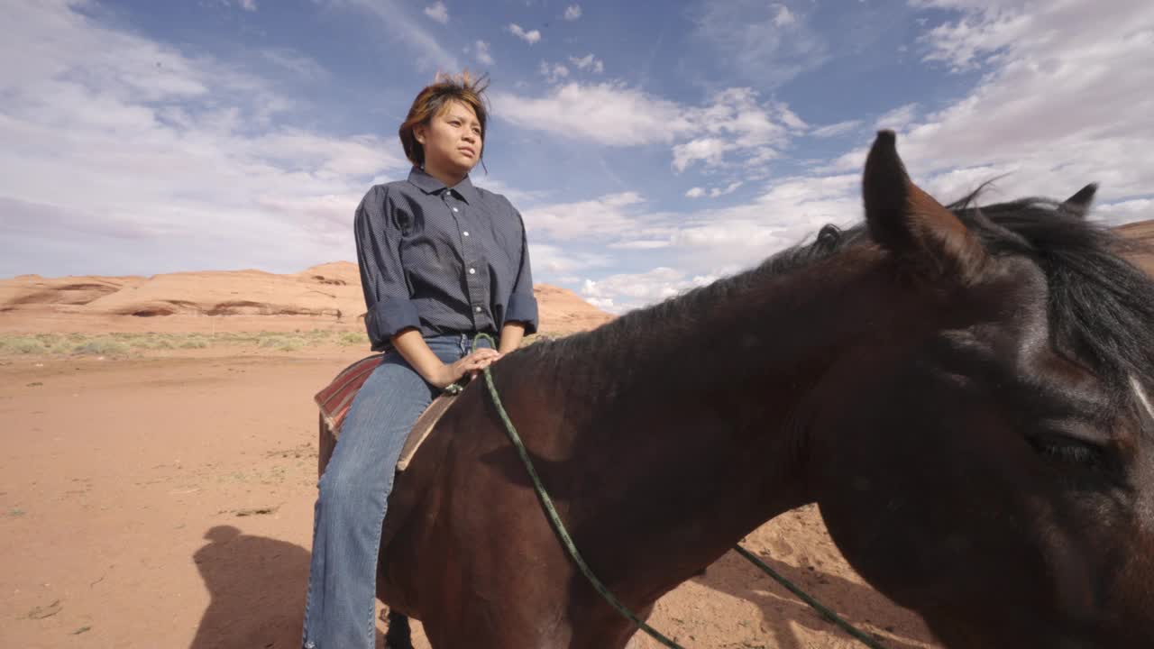 在美丽的天空下，16岁的纳瓦霍女孩坐在亚利桑那州纪念碑谷牧场畜栏附近的马上的视频肖像视频下载