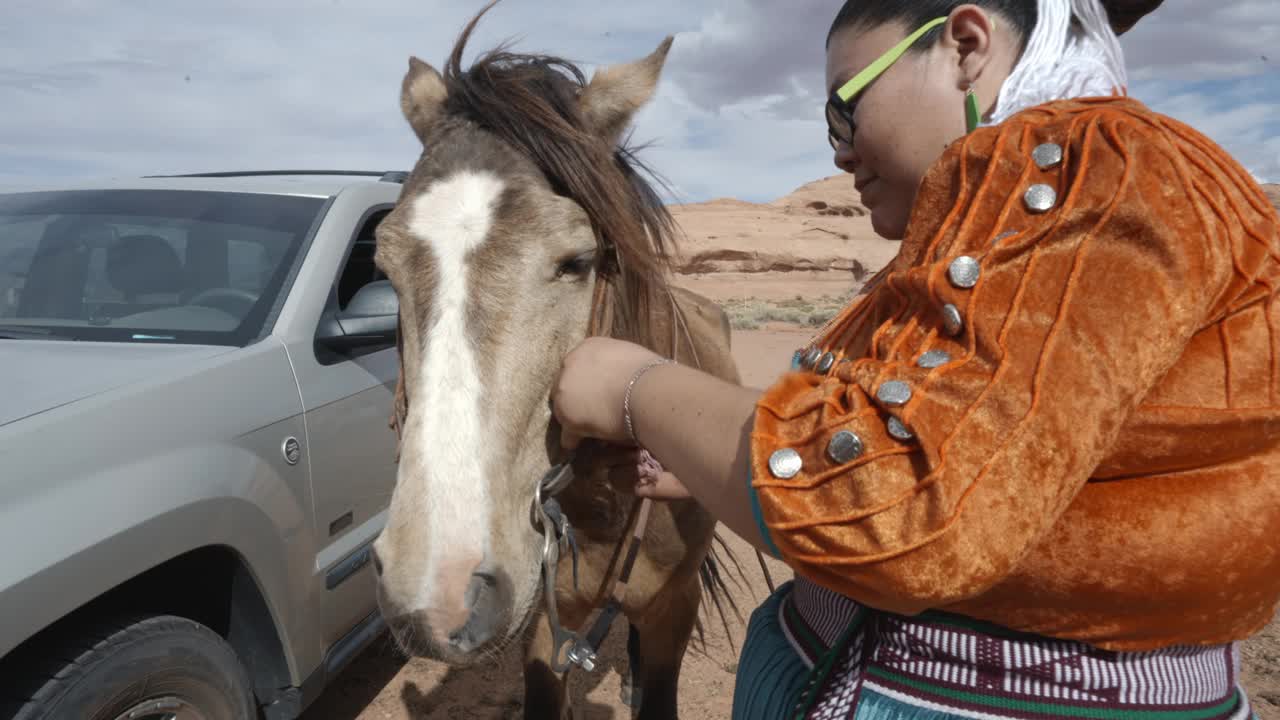 20多岁的年轻纳瓦霍妇女给她的马套上缰绳，准备在亚利桑那州的纪念碑谷骑马视频下载