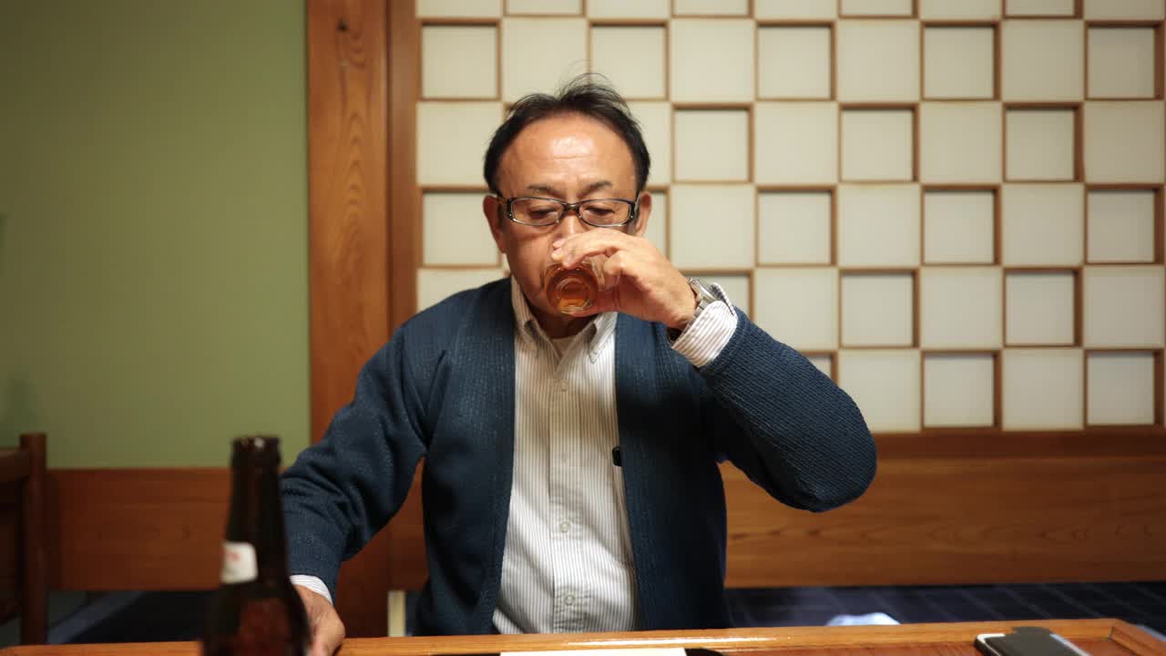 一位日本老人在传统的日本餐厅喝着一杯啤酒视频下载