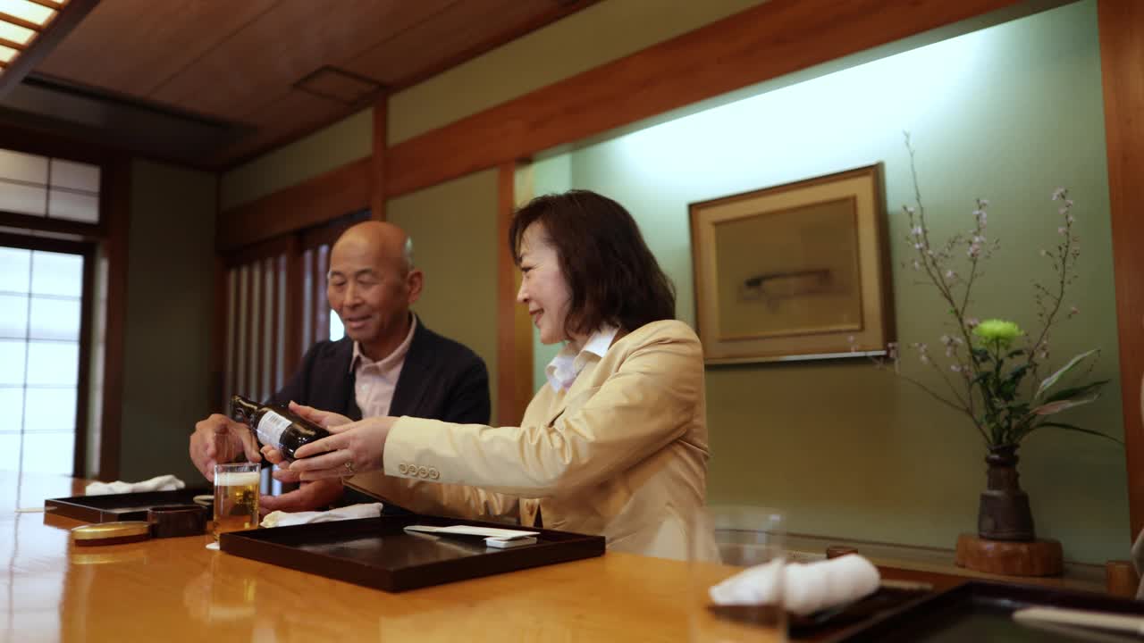 老夫妇在传统的日本餐厅倒啤酒视频下载