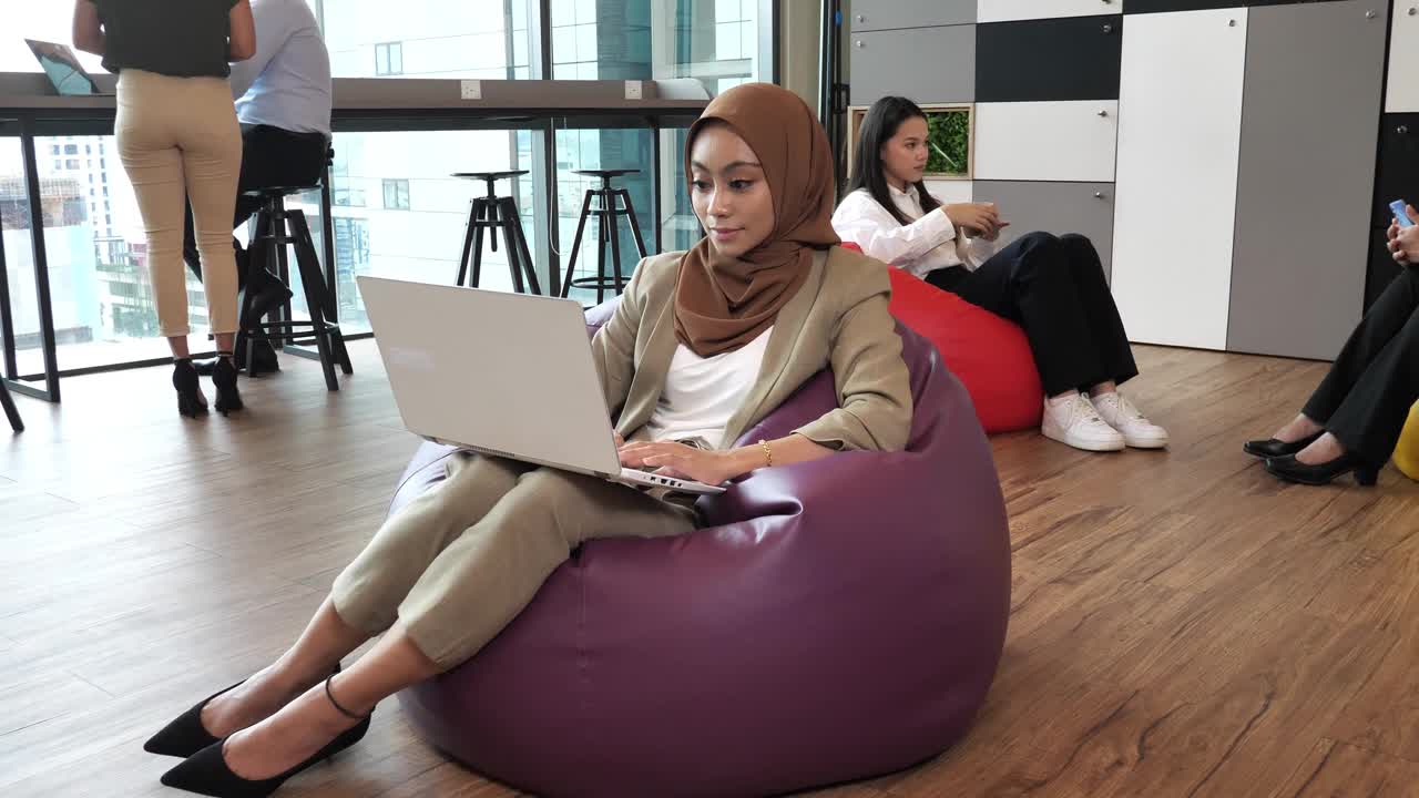 戴着头巾的亚洲女商人，穿着时髦的休闲装，在现代公司工作视频下载