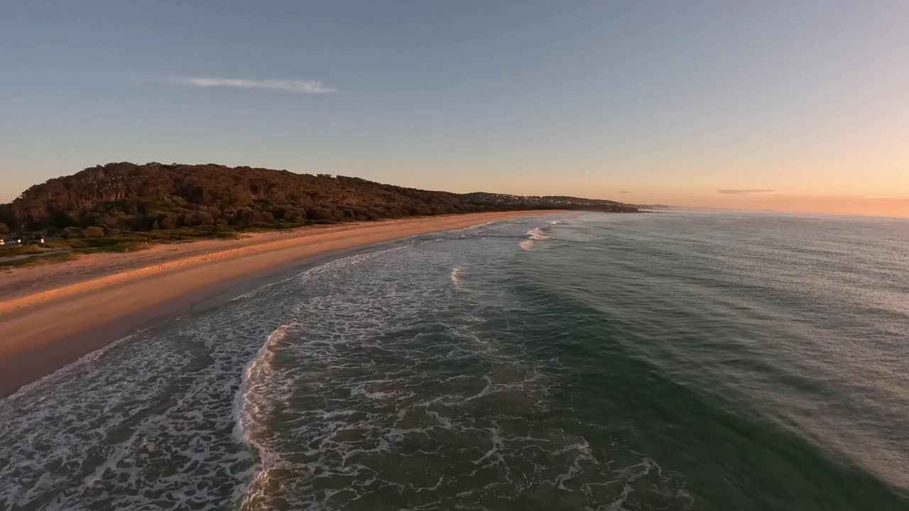 日出时低空鸟瞰海浪。视频下载