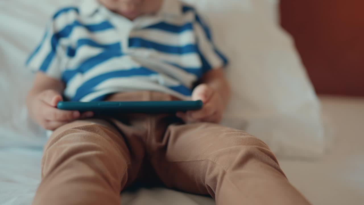 亚洲小男孩在家玩智能手机。视频下载