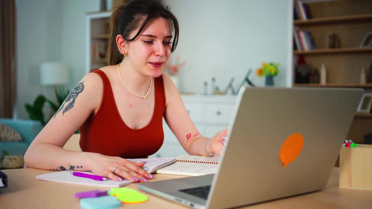 年轻快乐的女学生使用笔记本电脑观看网络研讨会在家写作视频下载
