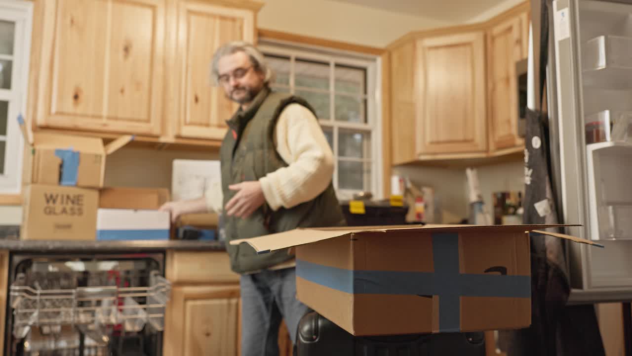新家布置:成熟的男人在搬进来的时候打开纸箱，整理厨房用具视频下载