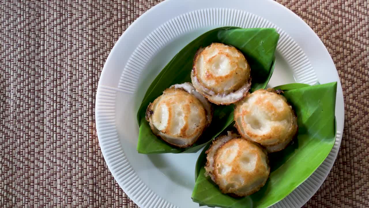 一对Kanom Krok杯或泰式油炸椰子蛋糕，放在香蕉叶上。泰国视频下载