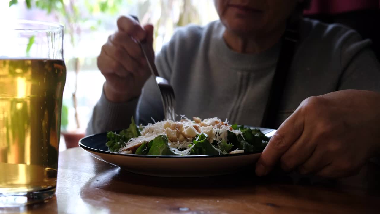 老年妇女在咖啡馆吃健康沙拉。绿色健康食品理念。什锦蔬菜沙拉视频下载