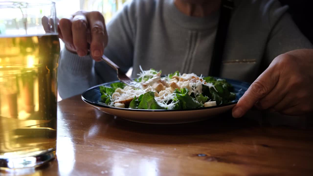 老年妇女在咖啡馆吃健康沙拉。绿色健康食品理念。什锦蔬菜沙拉视频下载