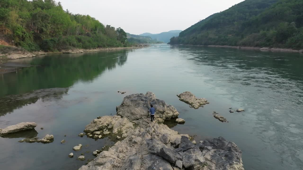 一个男人凝视着远方，在湄公河的岩石上休息视频下载