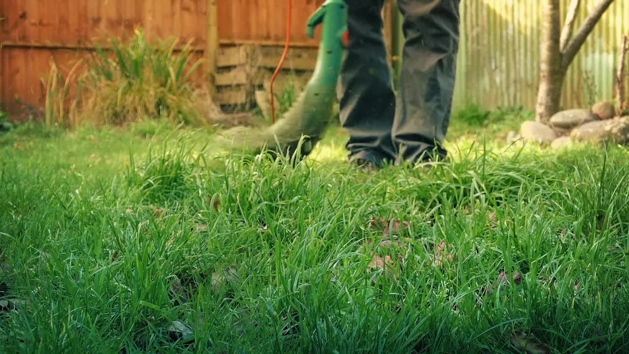 在阳光明媚的花园里使用草坪修剪器视频下载