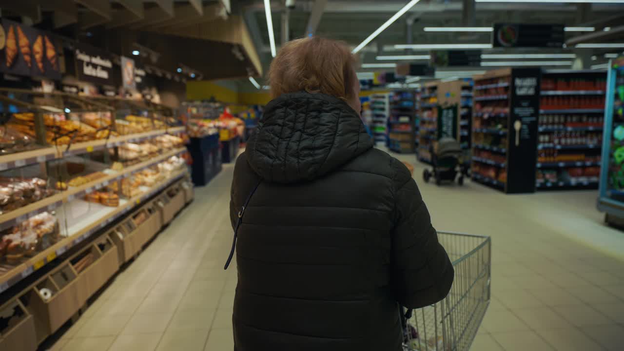 和奶奶一起逛超市:一段感人的视频，一位老太太推着手推车穿过整个食品市场，仔细地为她的家挑选食品。视频下载