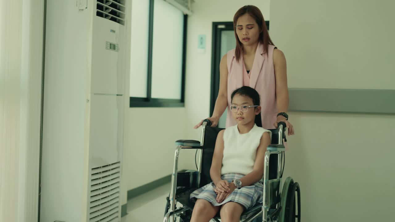 坐在轮椅上微笑的亚洲少女在医院与她的母亲真诚交谈，流露出喜悦和联系。视频下载