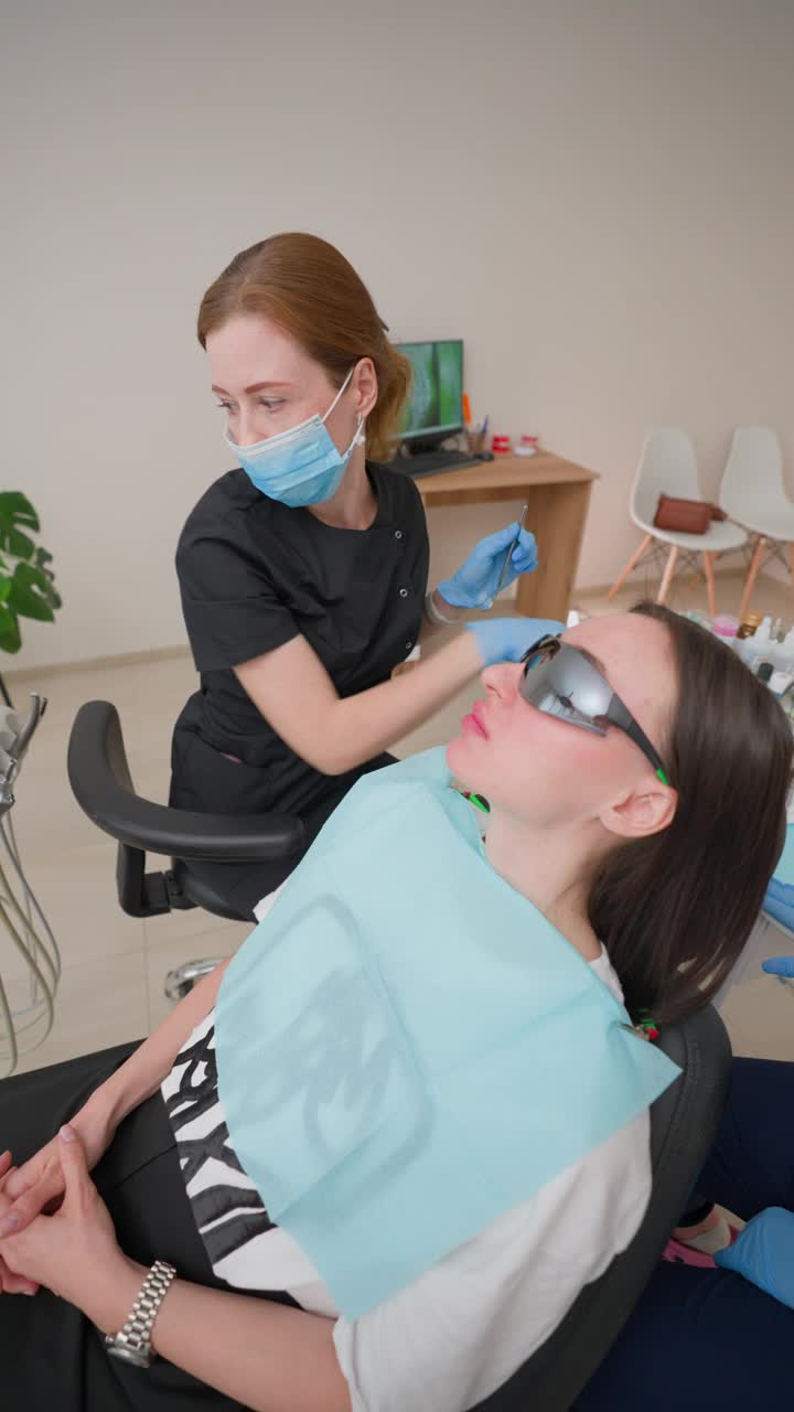一名戴牙套的妇女在诊所接受女牙医和助理的检查视频下载
