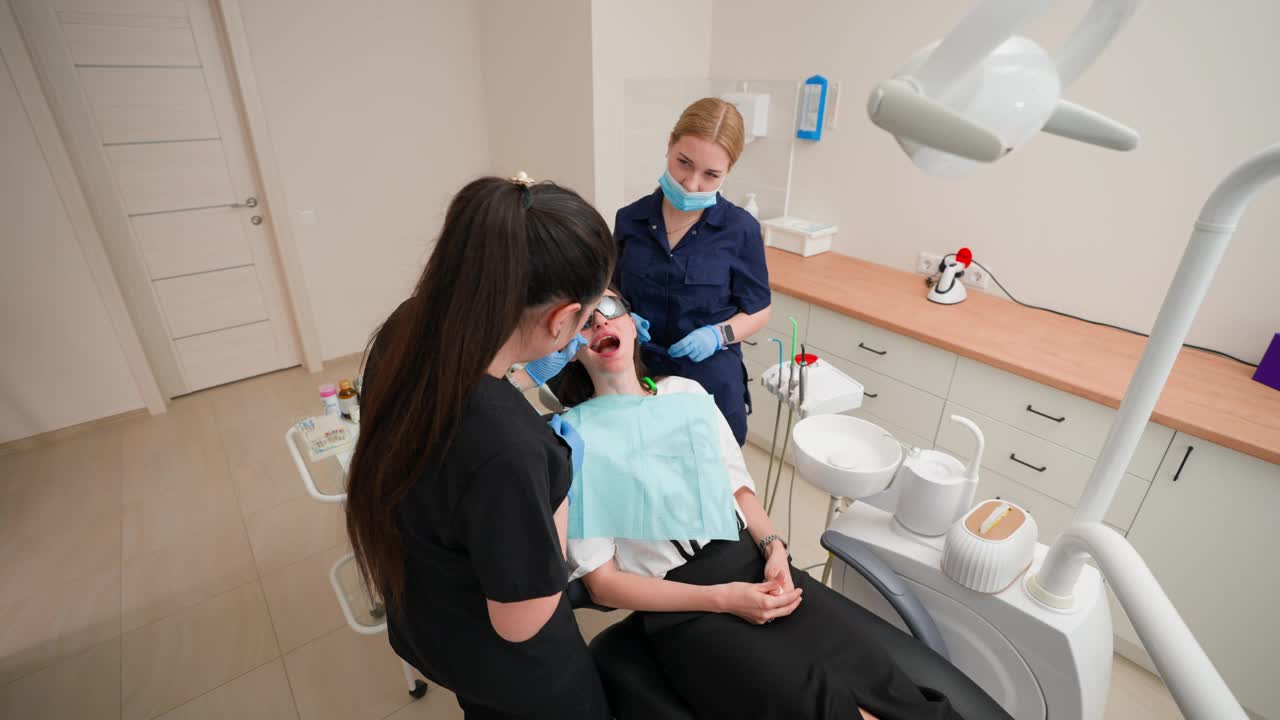 女牙医与助手在现代牙科诊所检查病人视频下载