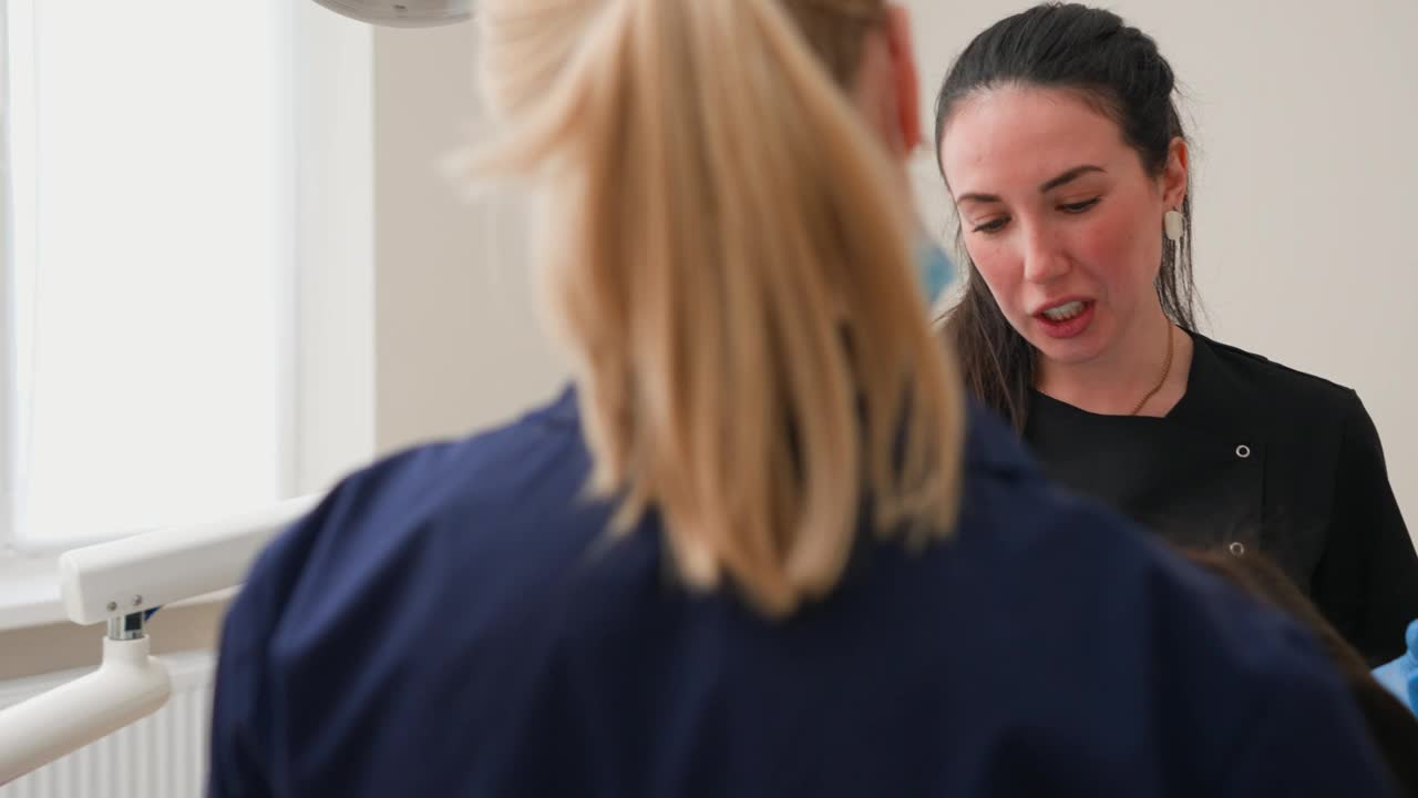 年轻的成年女牙医在光明牙科诊所告诉病人牙齿健康视频下载