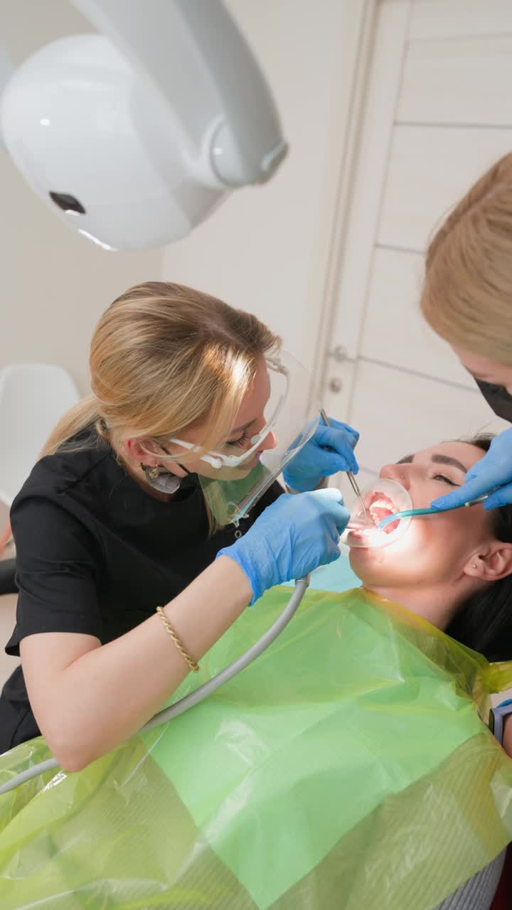 一名戴牙套的妇女在诊所接受女牙医和助理的检查视频下载