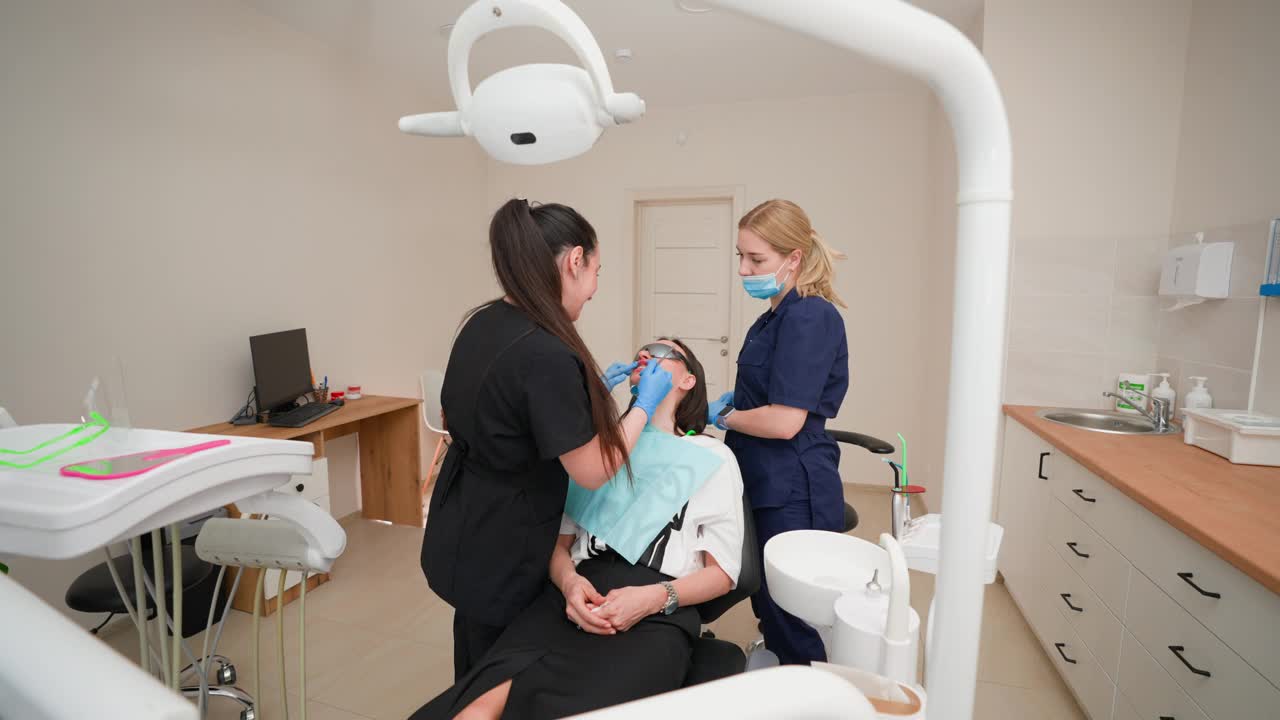 女牙医及助理在牙科诊所检查女病人口腔视频下载
