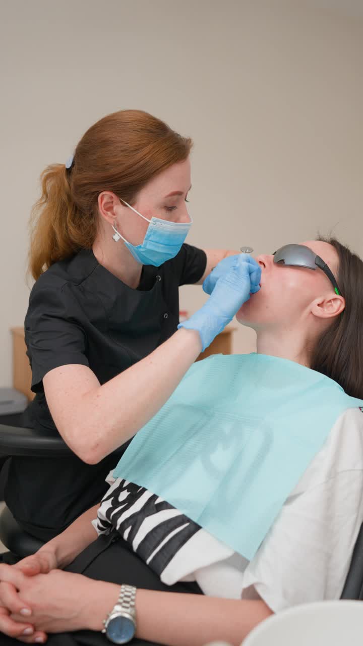 牙科医生用现代设备检查年轻的成年女病人视频下载