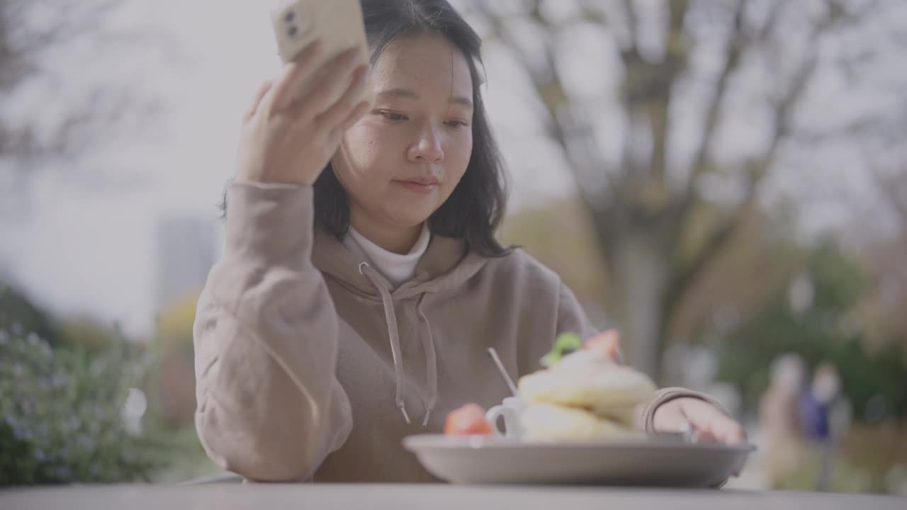 年轻的亚洲女性喜欢在咖啡馆吃甜食，并在社交媒体上分享她们的时间。视频下载
