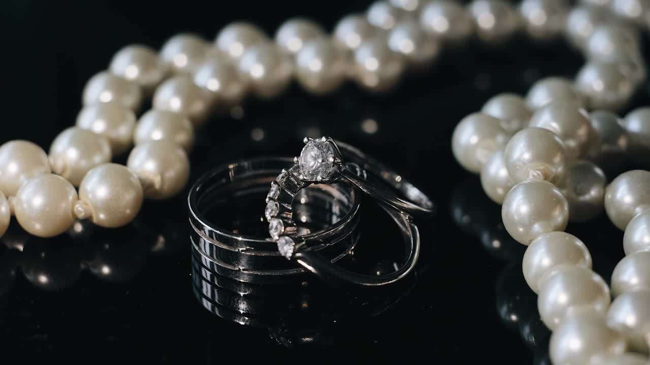 镜子桌上的珠子旁边放着两个戒指。这些珠宝被动态光照亮视频下载