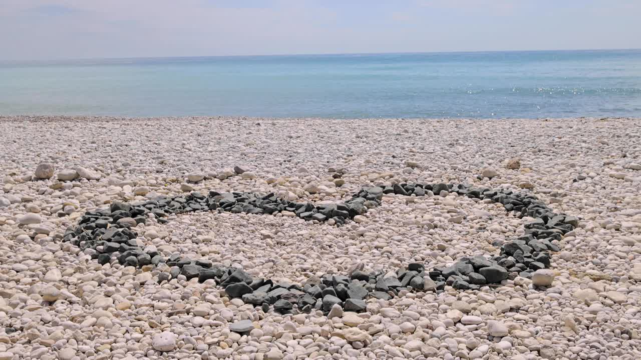 西班牙阿利坎特阿尔特亚美丽的海滩，在被称为普拉亚拉罗达的海滩上，展示了一个由岩石制成的心形视频下载