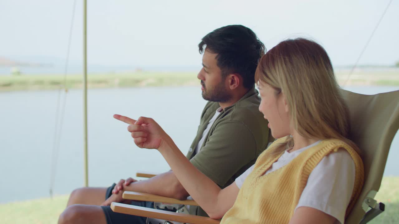 一个男人和一个女人坐在湖边的椅子上视频下载