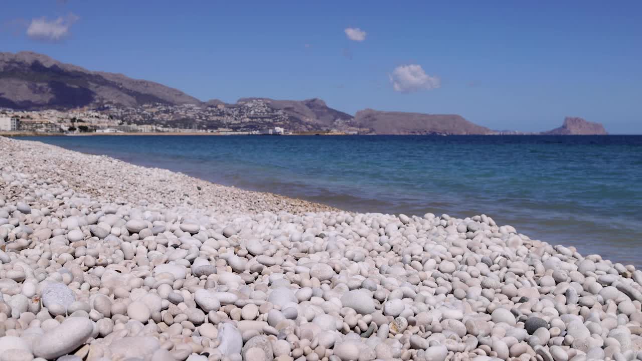 一个阳光明媚的夏日，西班牙阿利坎特的阿尔特亚镇的鹅卵石海滩前，海滩被称为普拉贾德L'埃斯皮戈视频下载