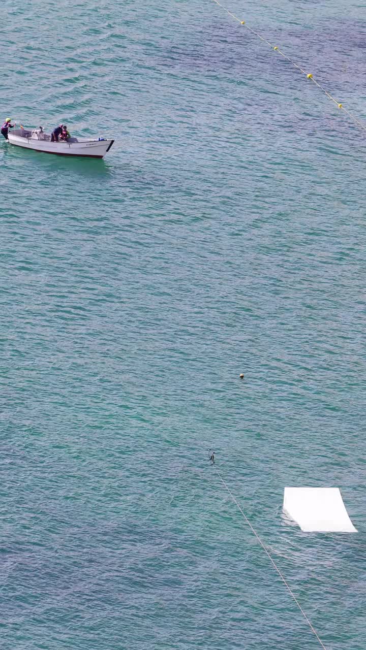 西班牙贝尼多姆的海洋肖像镜头显示，在著名的莱万特海滩上，一名滑水者在海洋中从绳索上滑水并跳过一个小斜坡视频下载