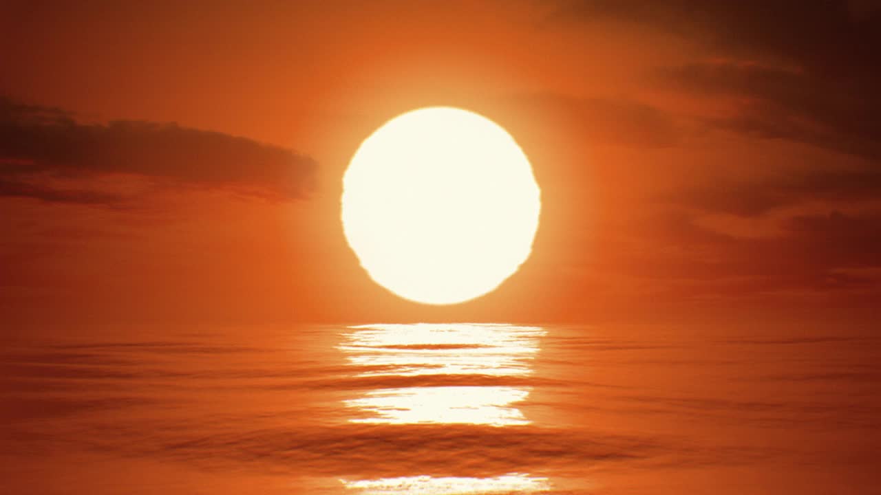 美丽清晰的日出(日落)在海浪上的特写循环3d动画缩放效果。大热的红色太阳在温暖的空气扭曲水面上无缝摆动。视频下载