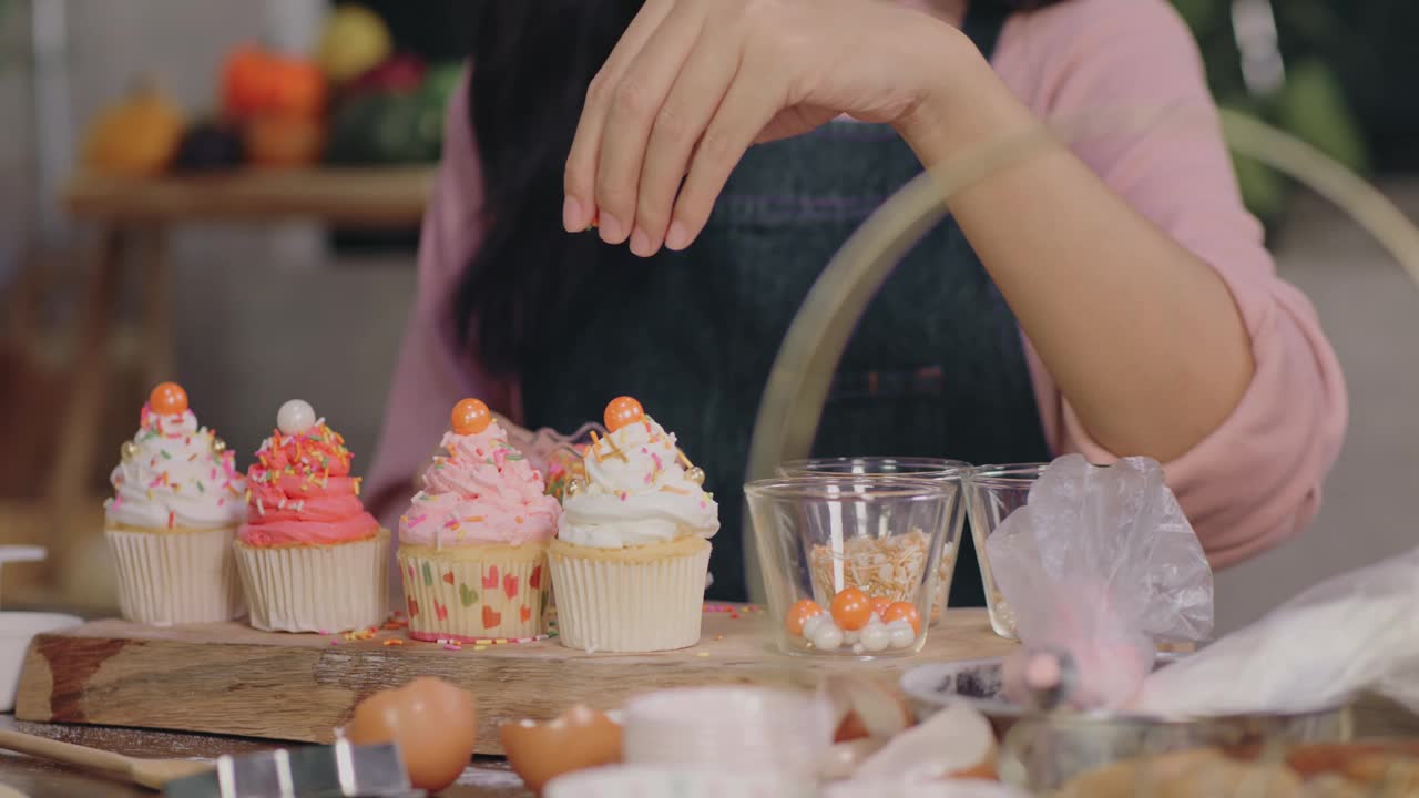 一位女士正在用糖屑和糖霜装饰纸杯蛋糕视频下载