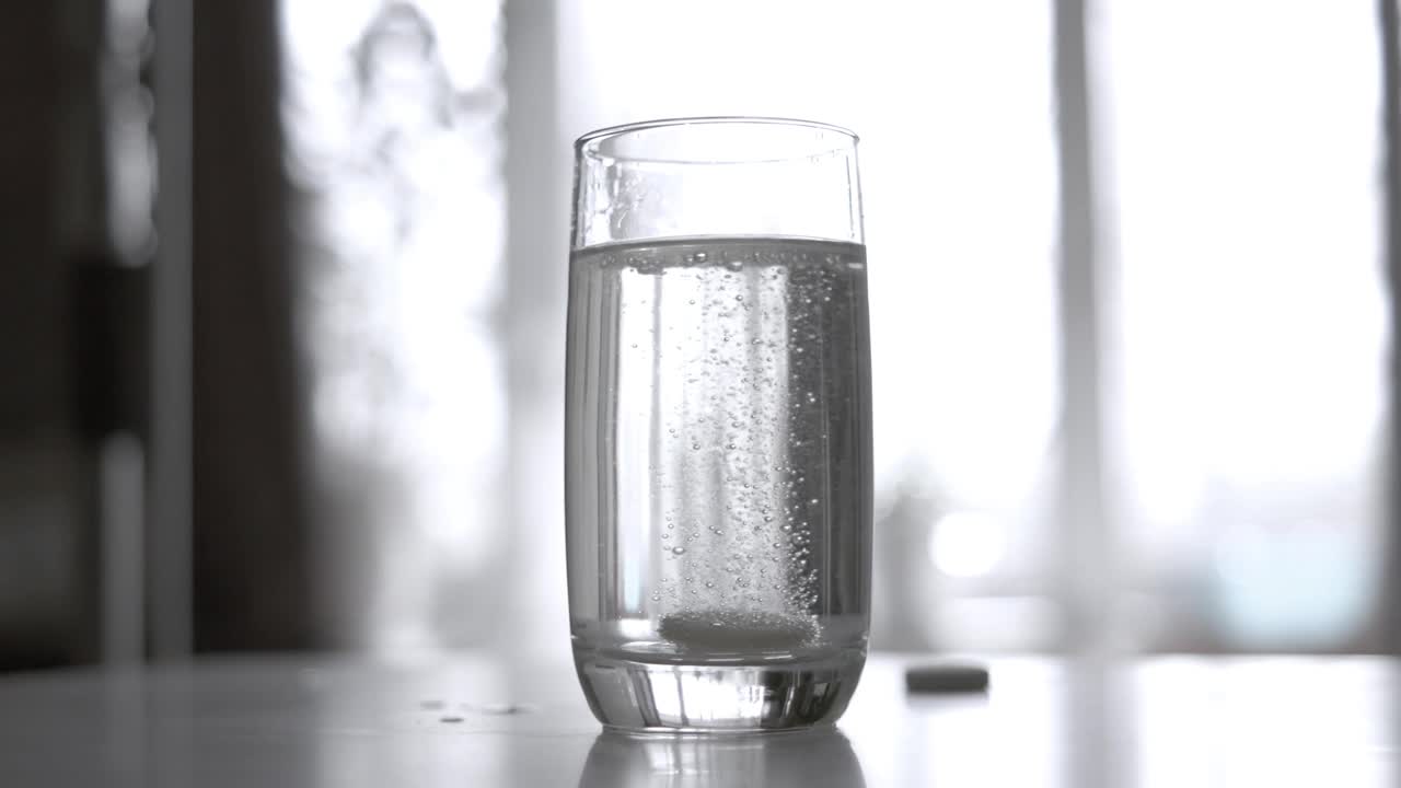 一杯水中的冒泡阿司匹林药片。可溶性片剂拍摄超慢动作相机1000 fps。视频下载