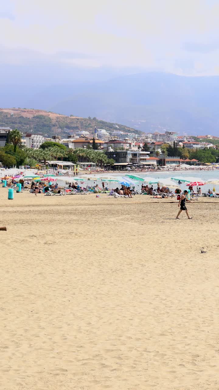 土耳其安塔利亚美丽海滩的人像镜头，展示了人们在夏天放松和享受海滩。视频下载
