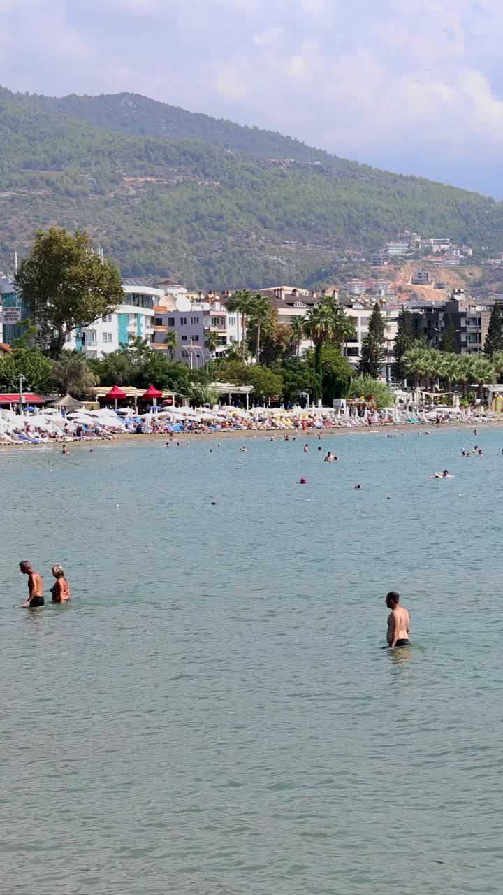 土耳其安塔利亚美丽海滩的人像镜头，展示了人们在夏天放松和享受海滩。视频下载