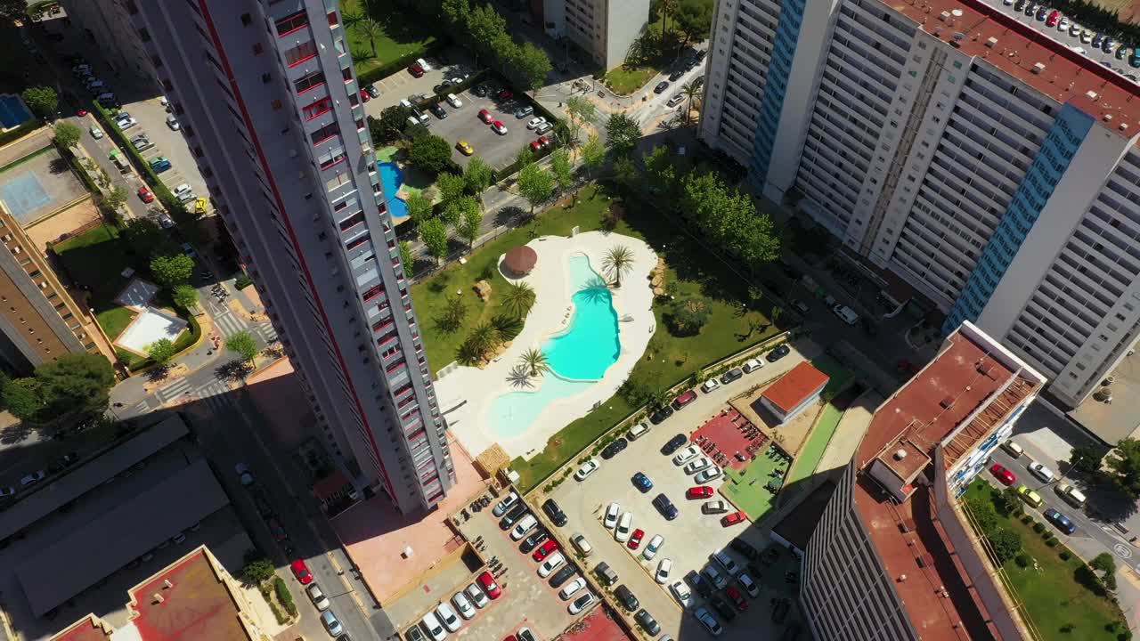 西班牙贝尼多姆镇的航拍画面显示，向下拍摄的是高层公寓，底部有游泳池和停车场视频下载