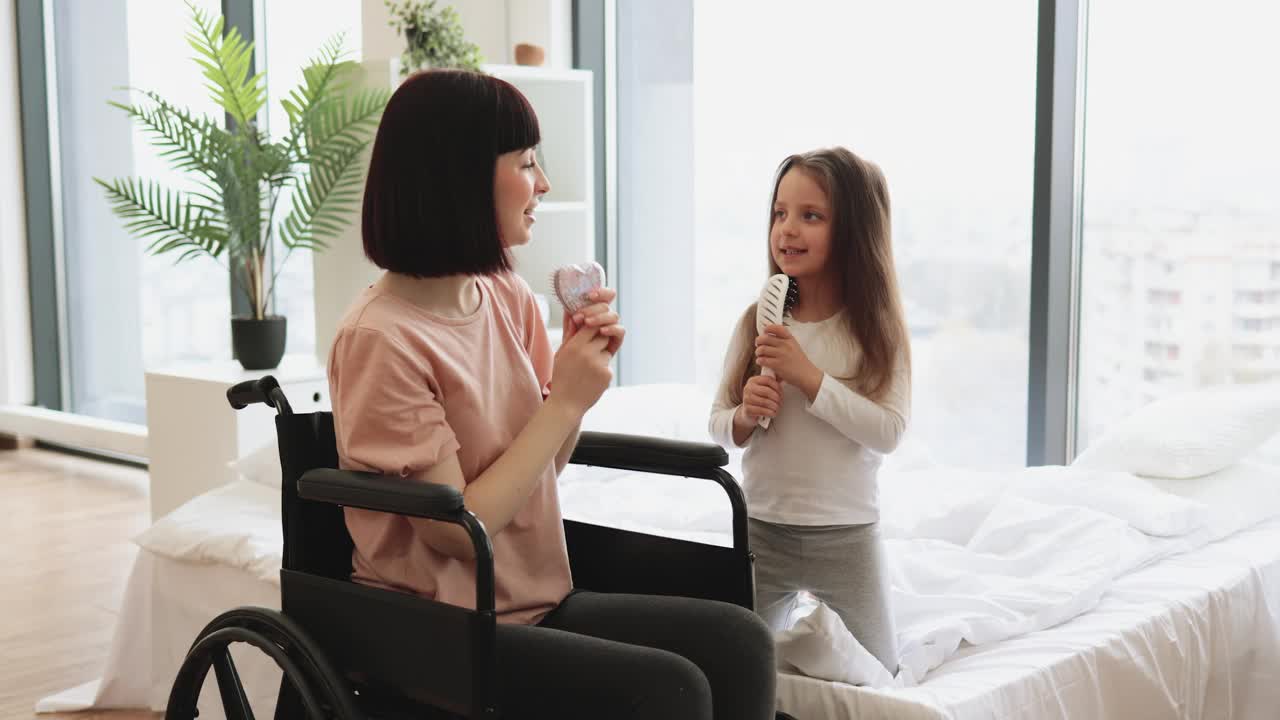 残疾母亲用梳子和她可爱的小女儿一起唱歌。视频下载