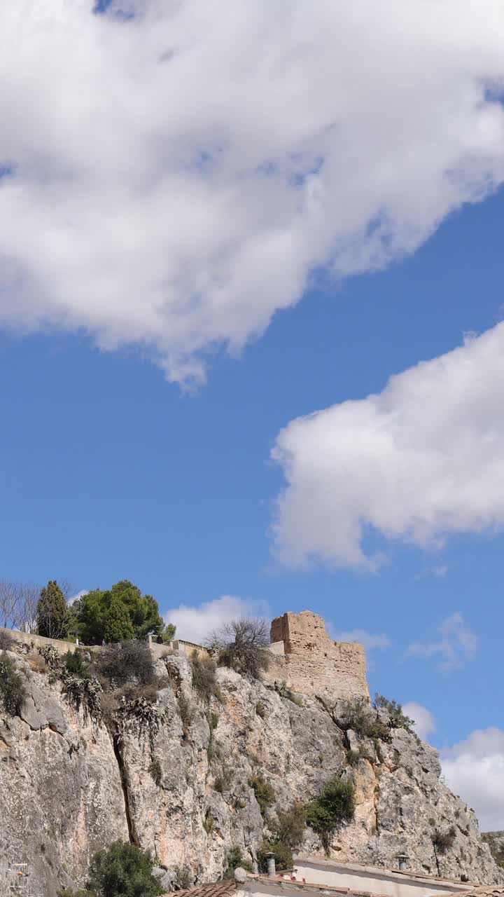 在一个阳光明媚的夏日，天空中有云，西班牙阿利坎特镇的瓜达莱斯特城堡(Castell de Guadalest)笼罩着瓜达莱斯特山谷视频下载